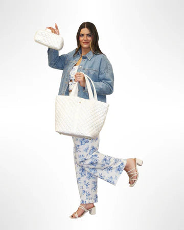 Woman holding a white, quilted nylon tote bag with a secure top zipper and a detachable striped strap.