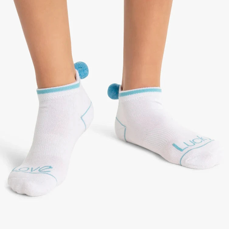 A pair of women's low-cut socks in white, with light blue pom pom accents as a decorative element.