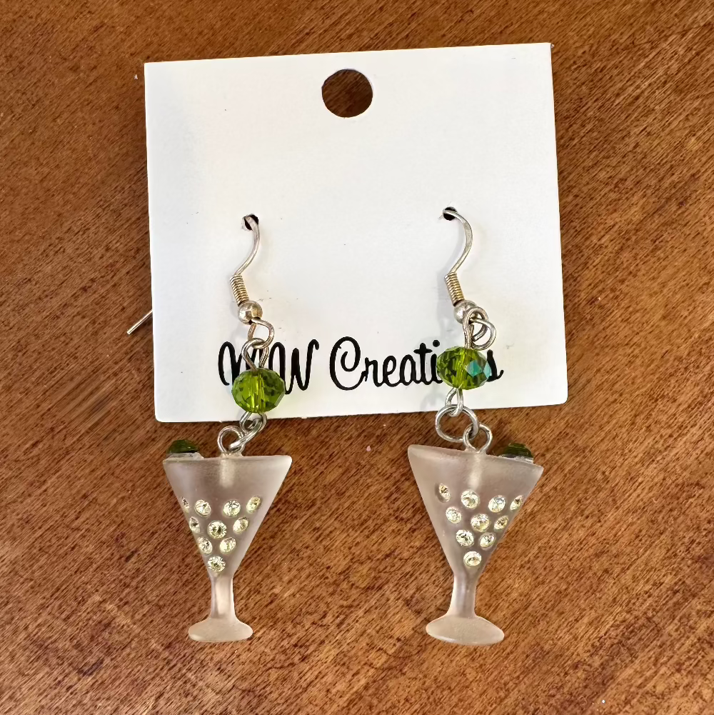 A pair of silver-colored martini glass earrings with green accents, displayed on a white card with 'MW Creations' written on it.