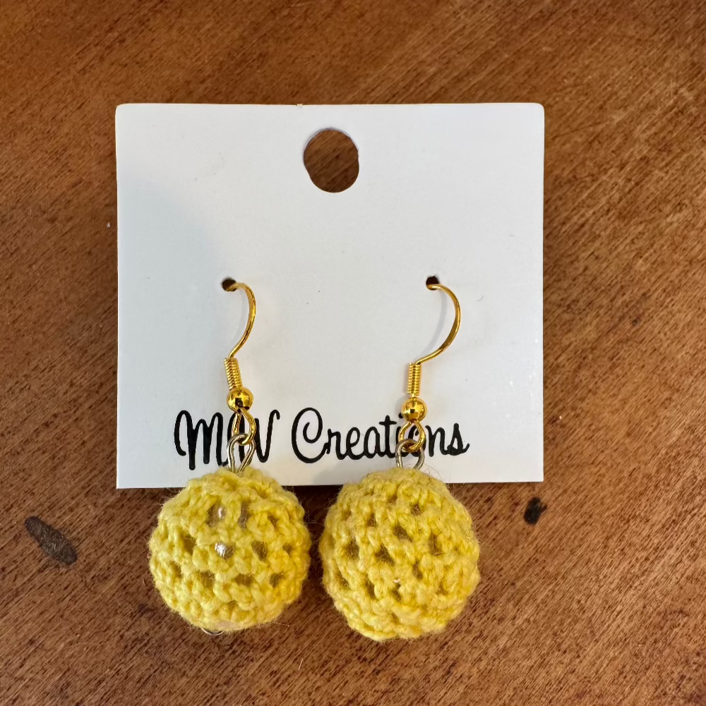 A pair of yellow, crochet pickleball earrings on a white earring card with 'MW Creations' printed at the bottom.