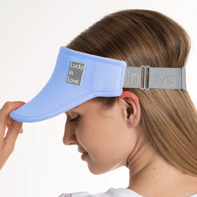 Side view of woman wearing a cool blue performance visor. French terry fabric on the inside headband has moisture wicking.