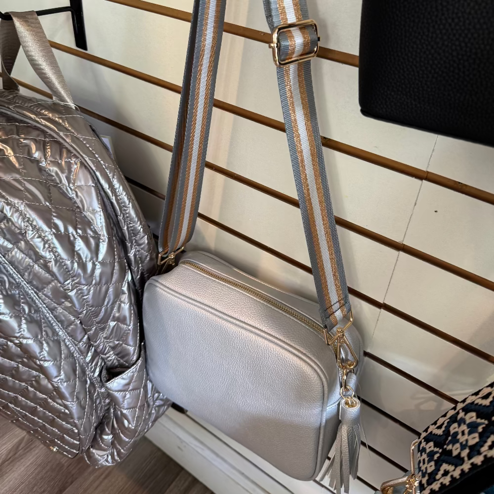 Silver handbag with striped strap .
