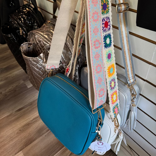 Aqua Blue bag with a colorful floral strap on a wooden floor.