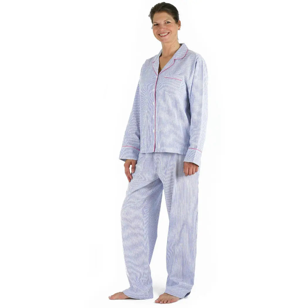 Woman wearing 100% cotton seersucker blue and white striped pajama set with pink piping