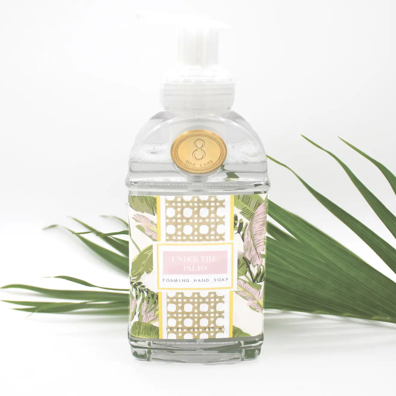 Foaming hand soap Under the Palms collection in pink and green tropical design of banana leaves and palms; the fragrance blends zesty citrus with cooling mint, and warm amber