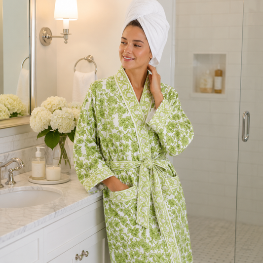 Woman wearing green ivy robe in bathroom with towel on her head.