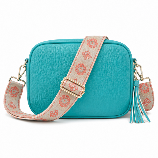 Ocean Blue crossbody bag featuring a wide adjustable shoulder strap with a coral floral pattern on a beige background and a matching tassel charm.