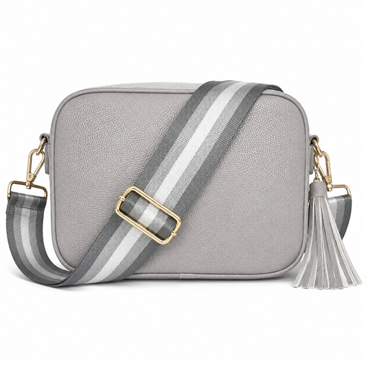 Silver faux leather crossbody bag with a wide gray and white striped strap, gold-tone buckle, and a matching gray tassel