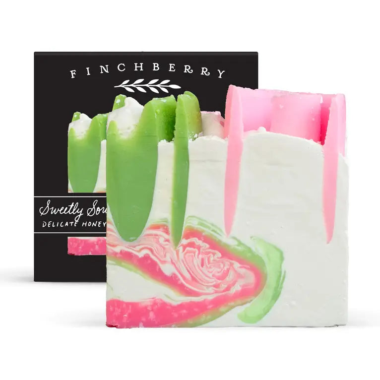 Colorful soap bars with green and pink swirls in front of a black Finchberry packaging.